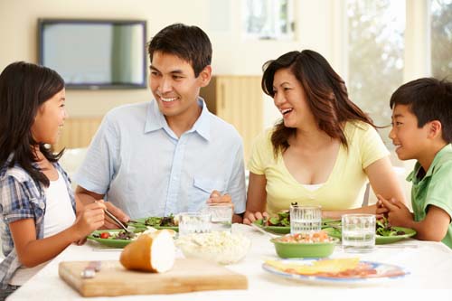 An Asian family sitting around the dinner table, talking together