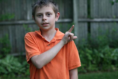 Boy in orange shirt making "L" sign with his hand