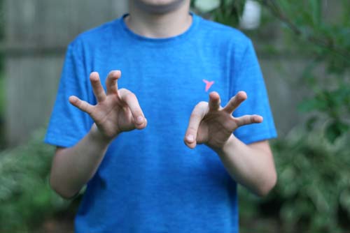Boy in blue shirt, gesturing "ok" with his fingers