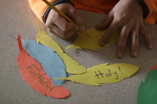 Girl coloring and writing words on feather art