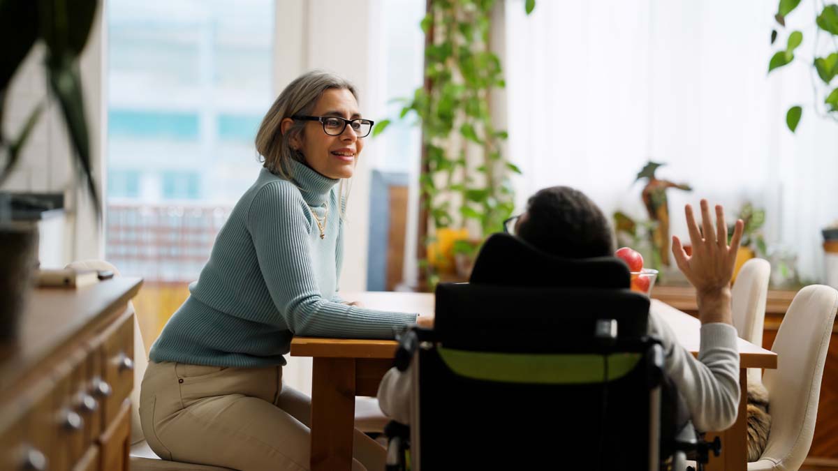 woman talking with her son, who is in a wheelchair, around a table