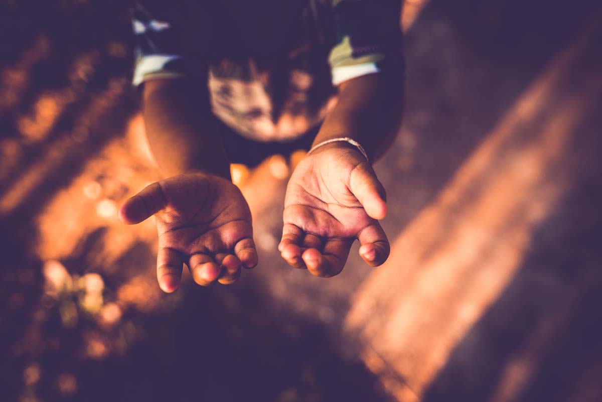 Child holding hands open to God in prayer.