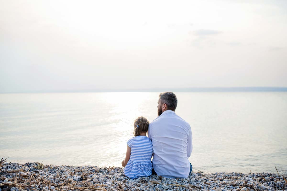father and daughter sitting on the shore quietly together